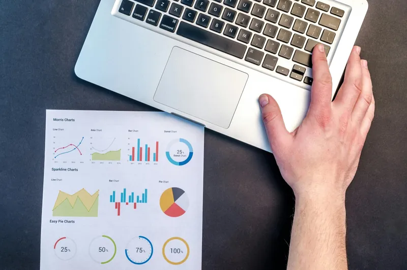 A laptop beside a printed set of performance charts