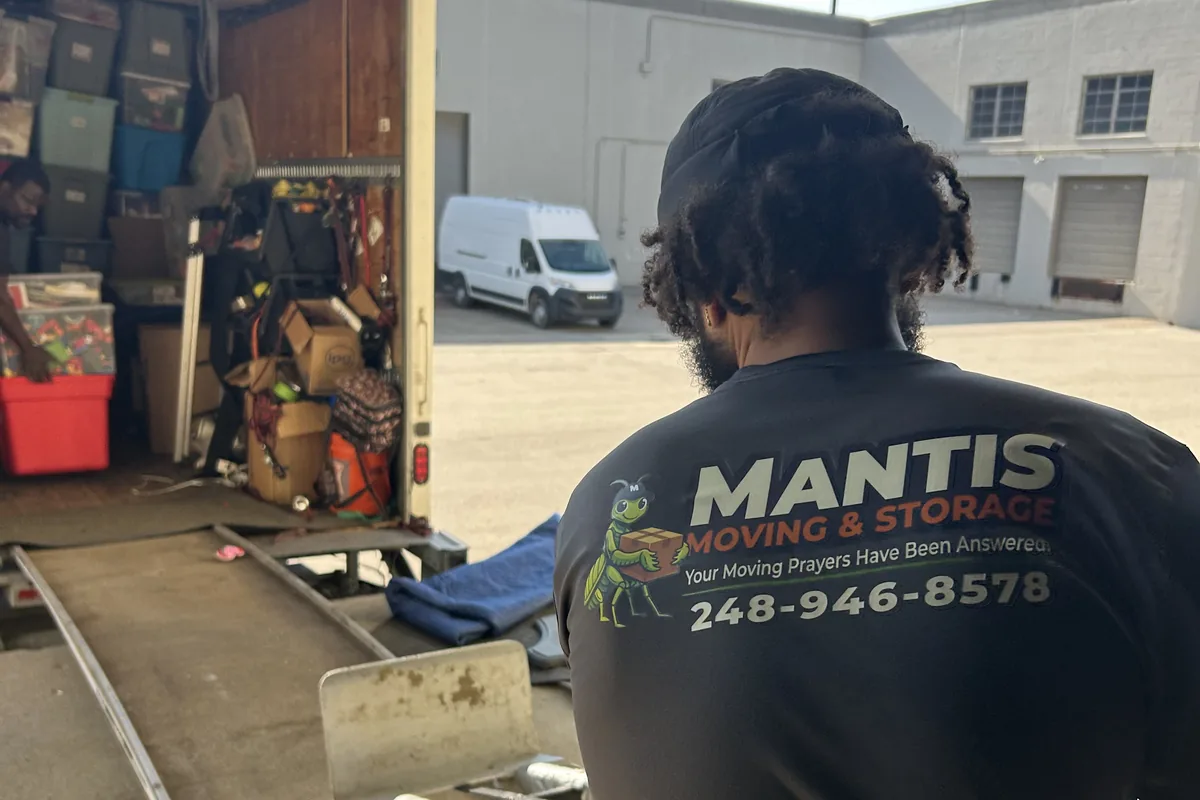 A Mantis Moving crew member wheeling a loaded dolly up a truck ramp
